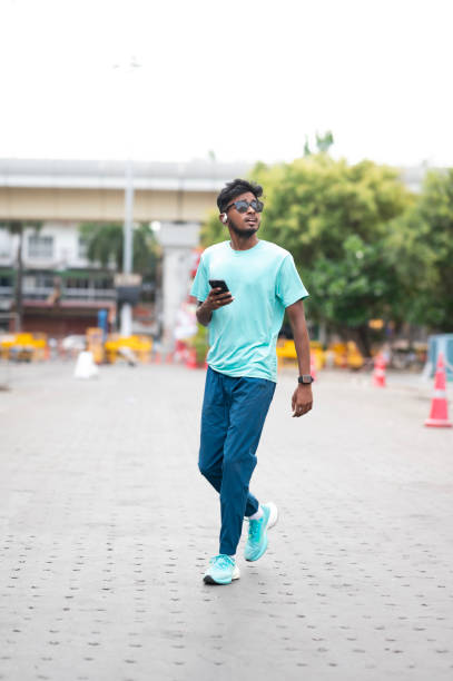 istock Stylish Young Adult Walking and Using Smartphone 2157935664