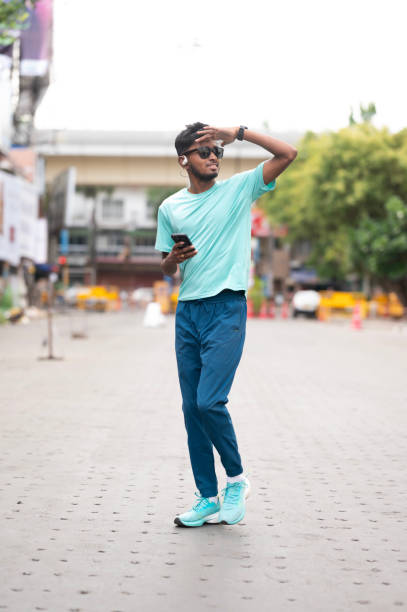 istock Stylish Young Adult Walking and Using Smartphone 2157935676