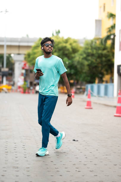 istock Stylish Young Adult Walking and Using Smartphone 2157935681