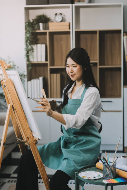 istock Pretty talented female painter painting on easel, making colorful sketches, creating marine landscape. Beautiful female artist painting with watercolor paints. Creativity and imagination concept 2157936340