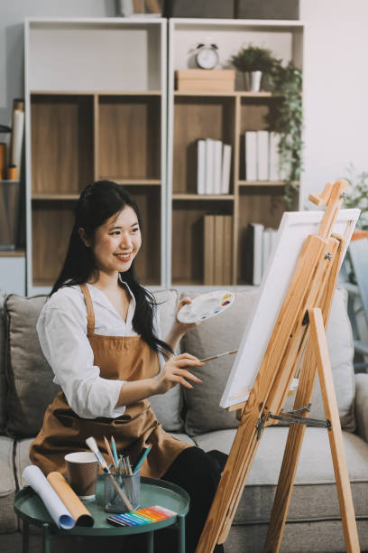 istock Pretty talented female painter painting on easel, making colorful sketches, creating marine landscape. Beautiful female artist painting with watercolor paints. Creativity and imagination concept 2157936341