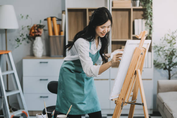 istock Pretty talented female painter painting on easel, making colorful sketches, creating marine landscape. Beautiful female artist painting with watercolor paints. Creativity and imagination concept 2157936352