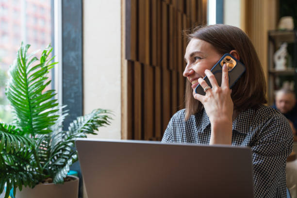 istock Happy woman sits at cafe table, talking phone and looking through window 2157937671