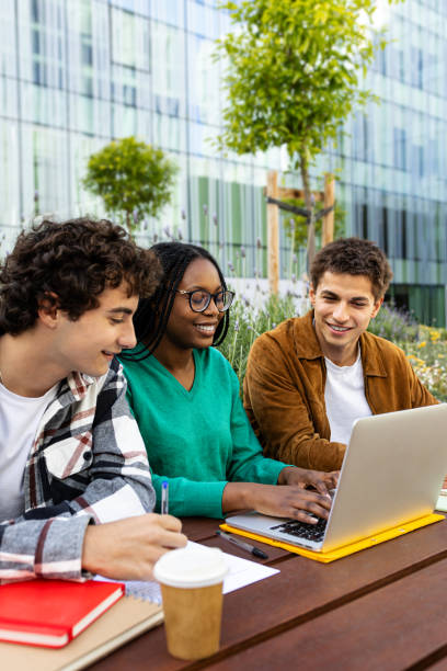istock Happy multiracial university students studying and doing homework together outdoor college campus using laptop. 2157939220