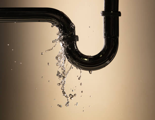 Drain leak water from pipe plumbing in bathroom as water always drop. Leaking water from chromium stainless steel pipe under sink. Low light background isolated