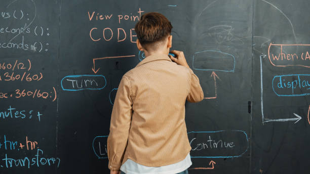 istock Back view of smart boy writing engineering prompt on blackboard. Erudition. 2157941075