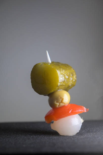 Banderilla bullfighter, typical Spanish appetizer with onion, red pepper, olive with anchovy and pickle on a toothpick, vertical