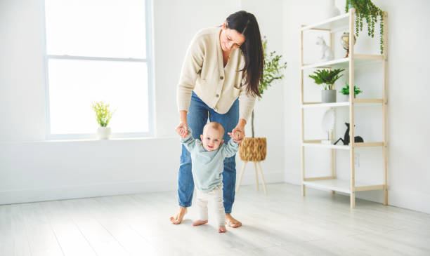 istock Happy little baby boy learning to walk with mother help at home. 2157948076