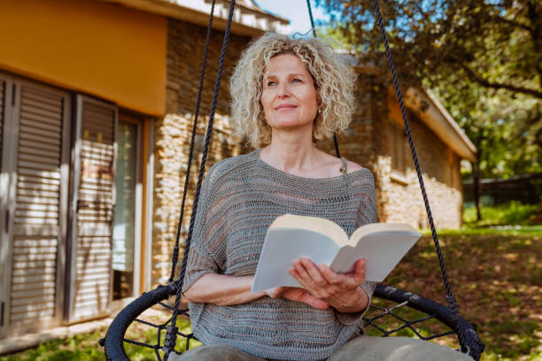 istock Middle aged woman reading a book in hammock 2157948646
