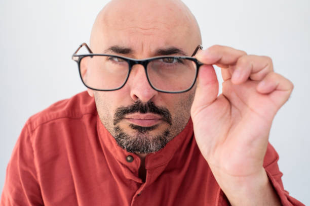 A close-up shot of a man taking off his glasses and looking directly into the camera. His expression is thoughtful and engaging, capturing a moment of introspection and direct connection with the viewer.
