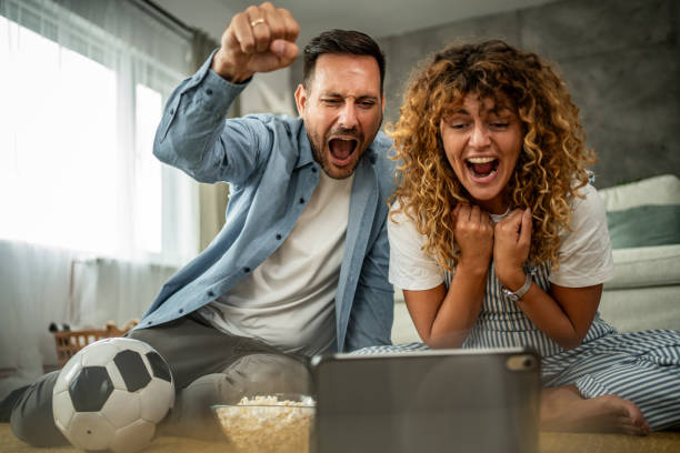 istock Couple watching soccer match together on digital tablet at home 2157951204