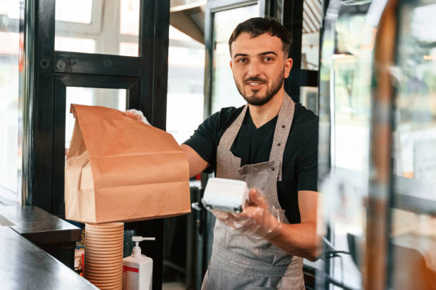 istock Payment by using terminal, order is ready. Man is serving delicious street food 2157951811