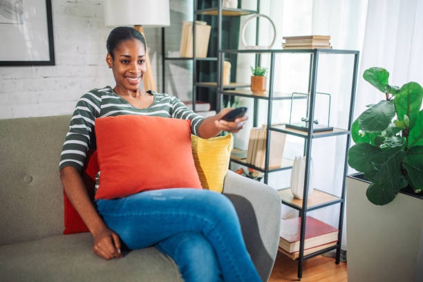 istock Young black woman watching TV on the sofa 2157952040