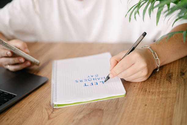 istock Woman writes by her left hand in a notebook the text left handers day 2157954799