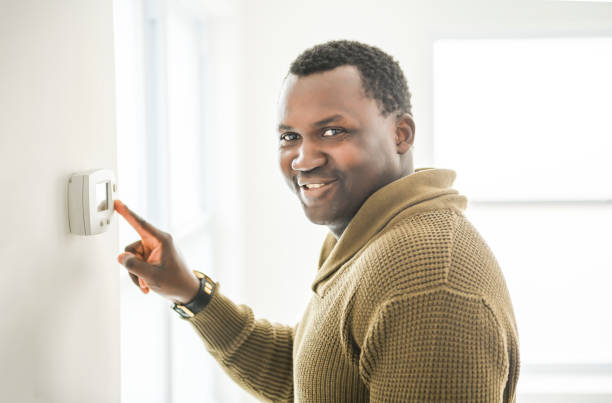 istock man choosing temperature on thermostat. Young focused guy pushing button home system. 2157955621