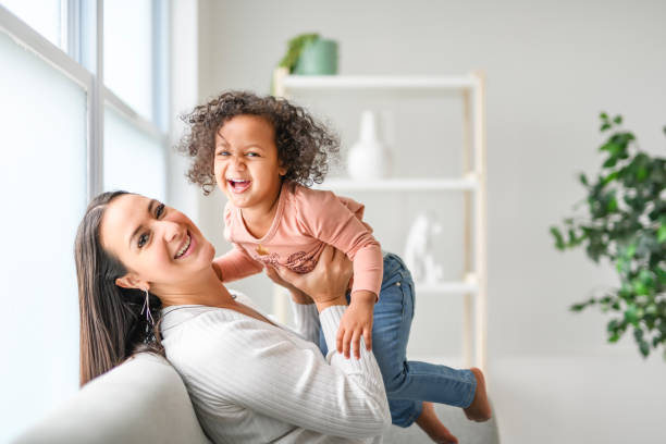 Mother with little daughter at home sofa