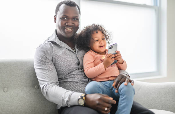 istock Happy Black American father with little daughter at home using cellphone 2157955821