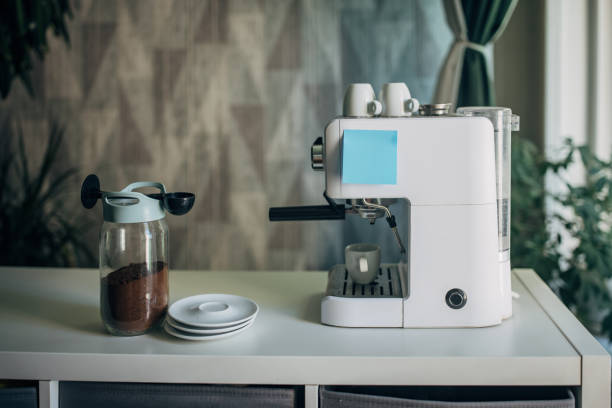 Espresso machine, glass espresso cups, with Asian cup, with biscotti on a white dish next to a stainless steel kitchen sink soft light through window