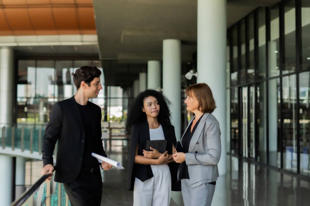 istock Three people stood in the hallway. Dress in work clothes They are holding documents and talking to each other. The scene is professional and serious. 2157956514