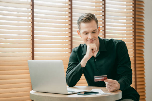 istock Young man using laptop with credit card for internet banking. Unveiling 2157960491