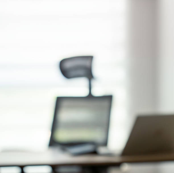 istock blurred workplace, computer chair, table and laptop against the background of a window 2157964669