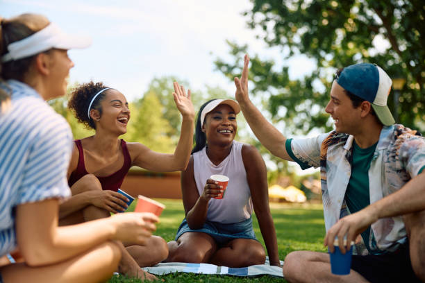 istock Cheerful friends giving high-five while relaxing in the park. 2157966350