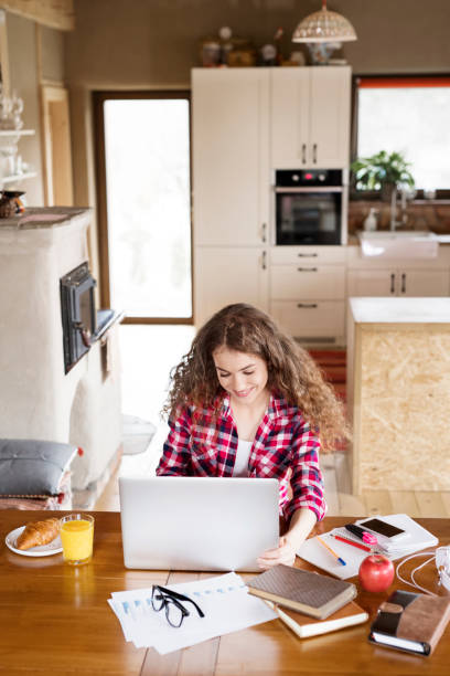 istock A beautiful university student is writing her thesis on a laptop, sitting at home on the couch. 2157969256