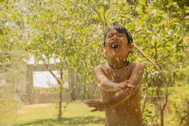 istock Little boy playing with water in the yard 2157973579