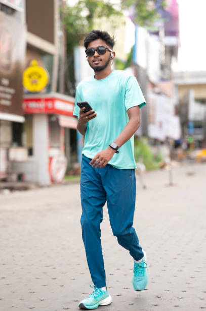 istock Stylish Young Adult Walking and Using Smartphone 2157974394