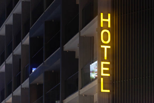 Larnaca, Cyprus - March 07 2024: Vertical yellow hotel sign at the egde of a building illuminated by night.