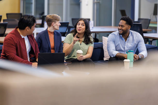 istock Diverse business group engaging in lively brainstorm with laptops in lobby. Focus on background 2157979794