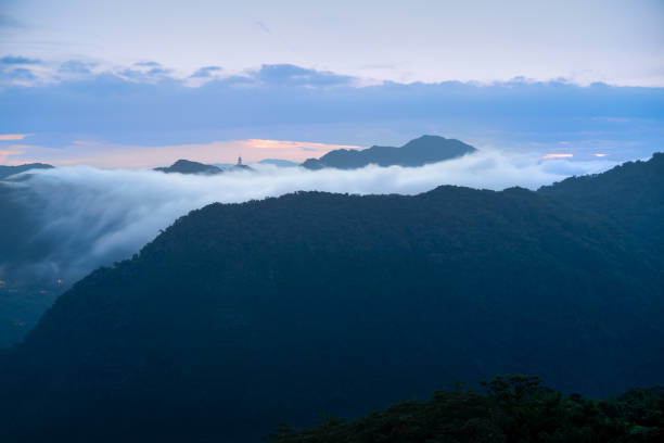 In the early morning before sunrise, the tranquil cloud waterfall flows slowly. View of the mountains surrounding Emerald Reservoir. Xindian District, Taiwan.