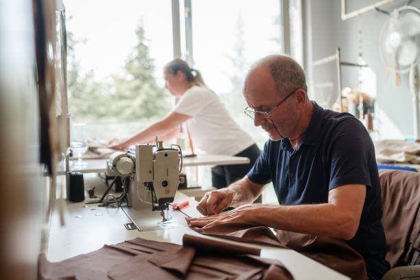 The tailor is sewing the fabric on the sewing machine.