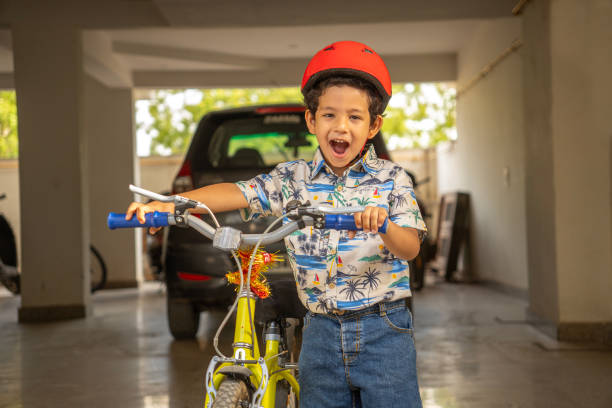 Portrait of cute boy wearing red helmet with bicycle in parking lot during weekend