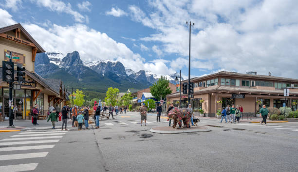 Canmore, Alberta, Canada – June 16, 2024:  People enjoy Main Street in the downtown with Mount Rundle in the Background