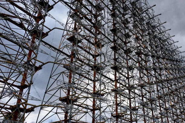 A series of metallic constructs, heavily wired, showing signs of rust. Duga is a Soviet over-the-horizon radar station for an early detection system for ICBM launches. una serie de construcciones metálicas, fuertemente alambradas, que muestran signos de óxido. duga es una estación de radar soviética sobre el horizonte para un sistema de detección temprana para lanzamientos de misiles balísticos intercontinentales.