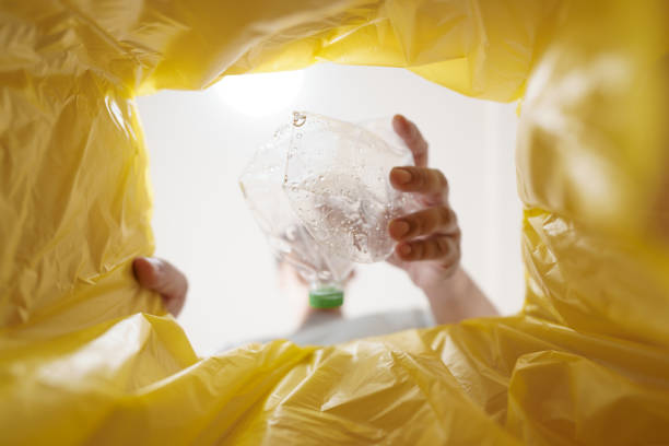 Image from inside yellow recycling bag of man throwing empty plastic bottle in recycling bin Home recycle eco green zero concept