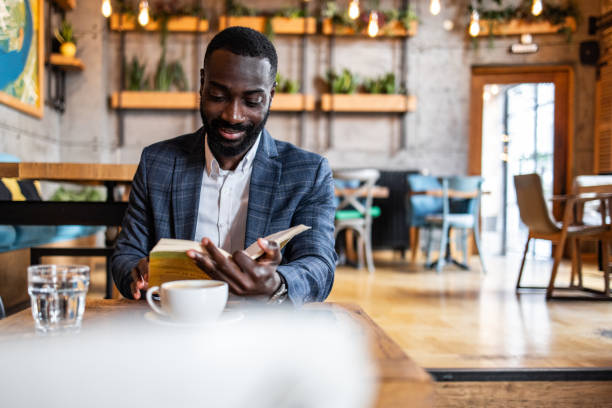 istock A young black man, a business man, elegantly dressed, reads a book in a cafe 2157995003