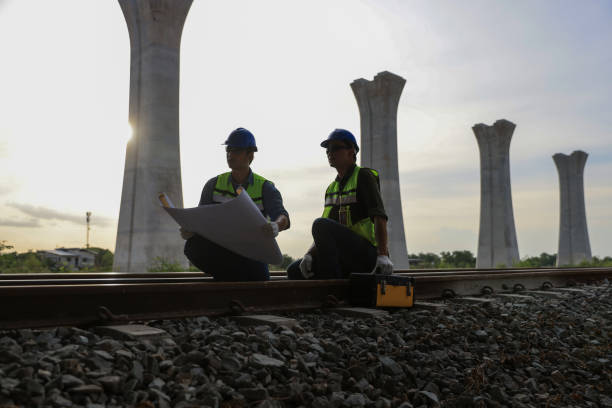 istock Two male railway technicians are reviewing blueprint drawings and inspecting the construction of a high-speed railway with the Skytrain stanchions pillars in the background. 2157995264