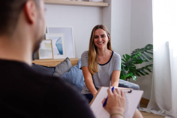 istock Young woman smiling and talking to therapist taking notes during therapy session 2157998245