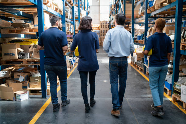 istock Rear view of warehouse team and manager walking through storage racks 2157998581