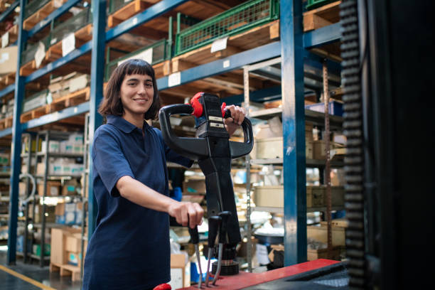 Young woman operating an electric forklift pallet jack at warehouse