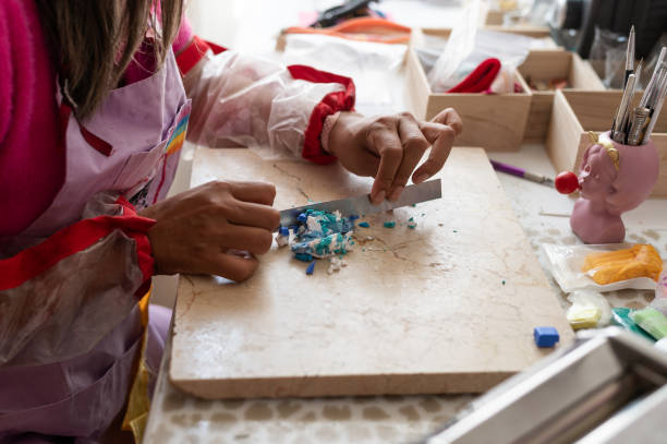istock Craftwoman mixing polymer clay with metal spatula in her workshop 2158000464