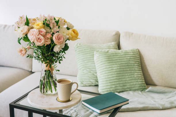 Coffee cup, flowers, and notebook on a glass table next to a couch