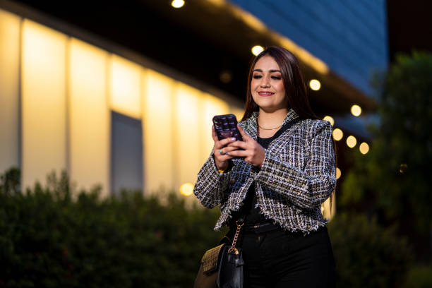 istock executive woman at night checking her cell phone 2158004663
