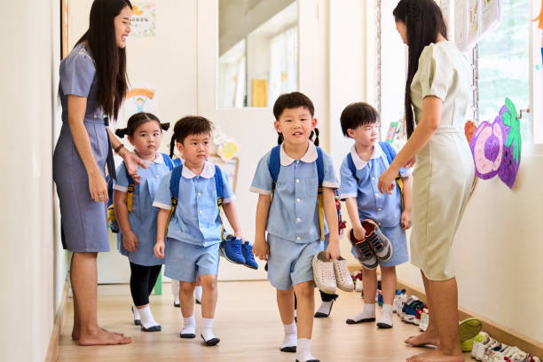istock Two teachers direct children to take off their shoes before class 2158008282