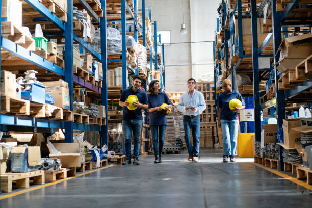 istock Group of warehouse workers with manager walking together through storage racks 2158009602