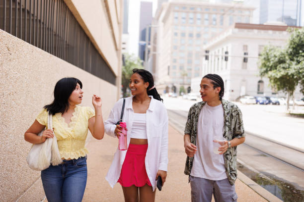 istock Front view of three students walking down the street and talking 2158012319