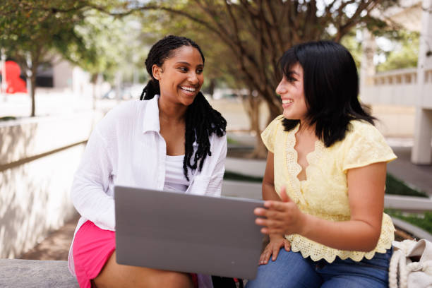 istock Smiling female students working on a laptop outdoors 2158012823