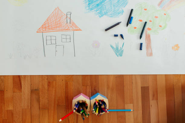 Above shot of child drawing on a paper on the floor